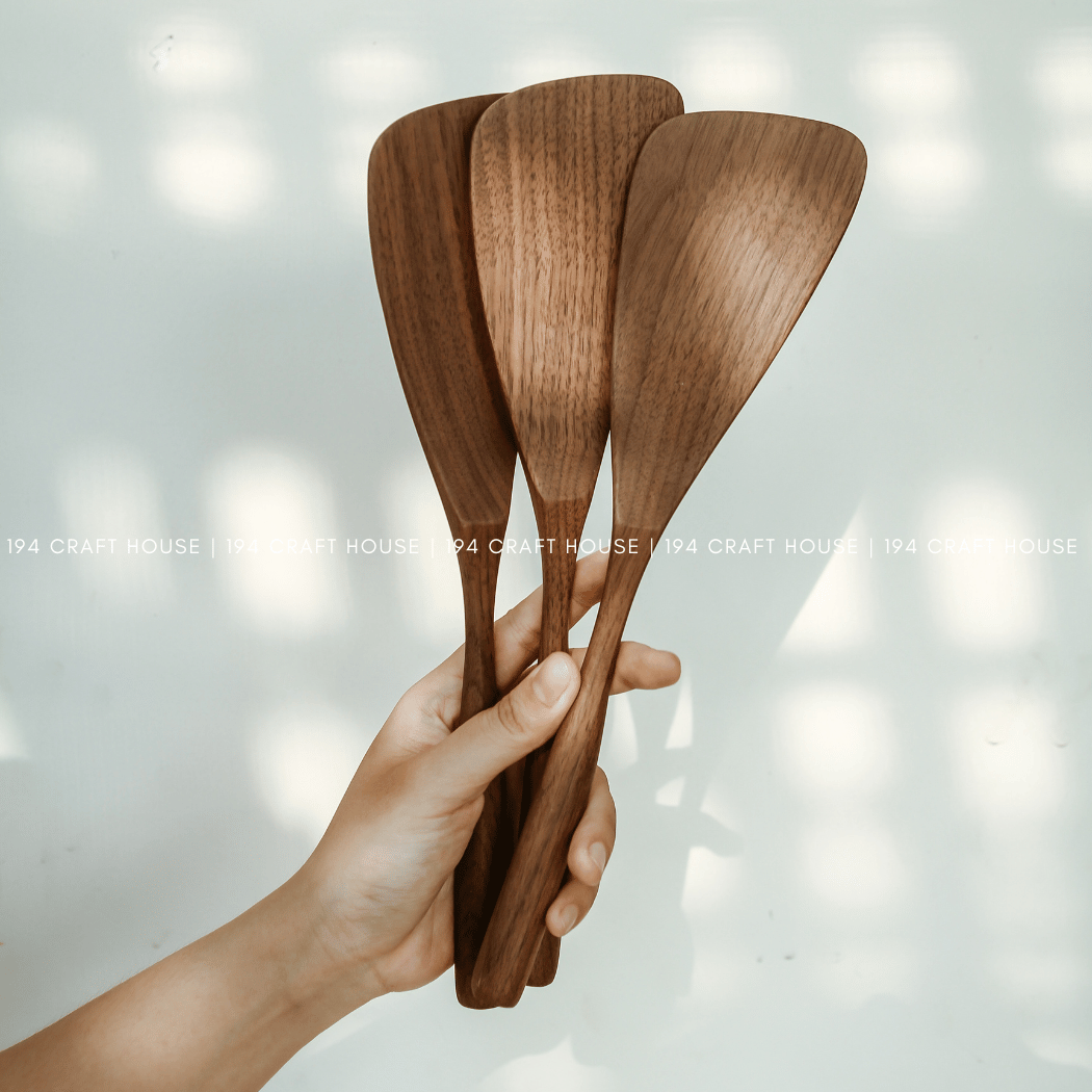 Three handcrafted walnut wood spatulas showing natural grain variations
