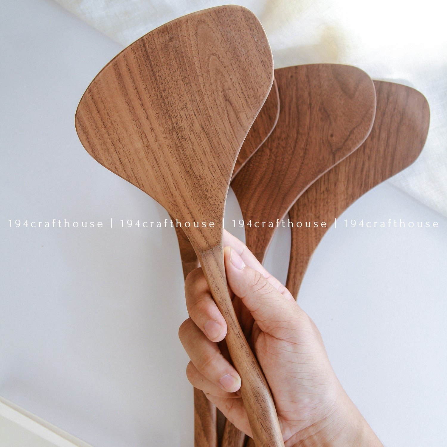 Hand holding a large 13-inch walnut wood spatula with a broad handcrafted head