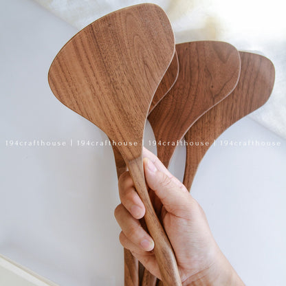 Hand holding a large 13-inch walnut wood spatula with a broad handcrafted head