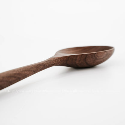 Low side view showing the walnut spoon bowl, raised rim, and long handle