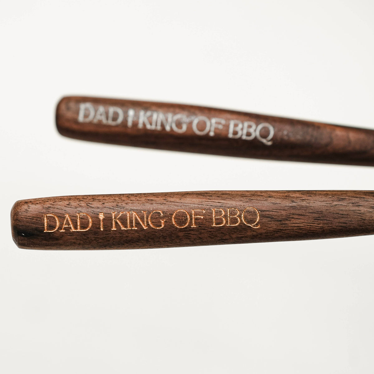 Close view of engraved BBQ lettering along two dark walnut spoon handles