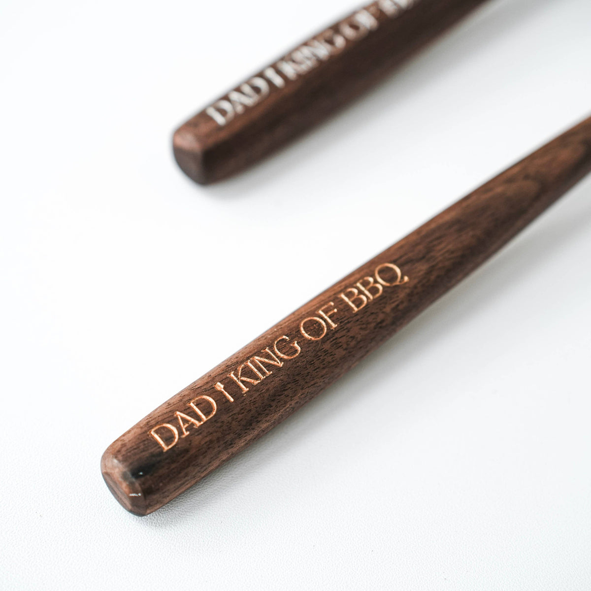 Close-up of one walnut spoon handle with the “DAD I KING OF BBQ” engraving visible