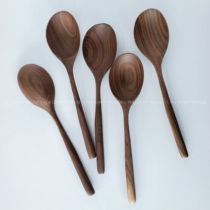 Set of five large walnut wooden spoons on a white background