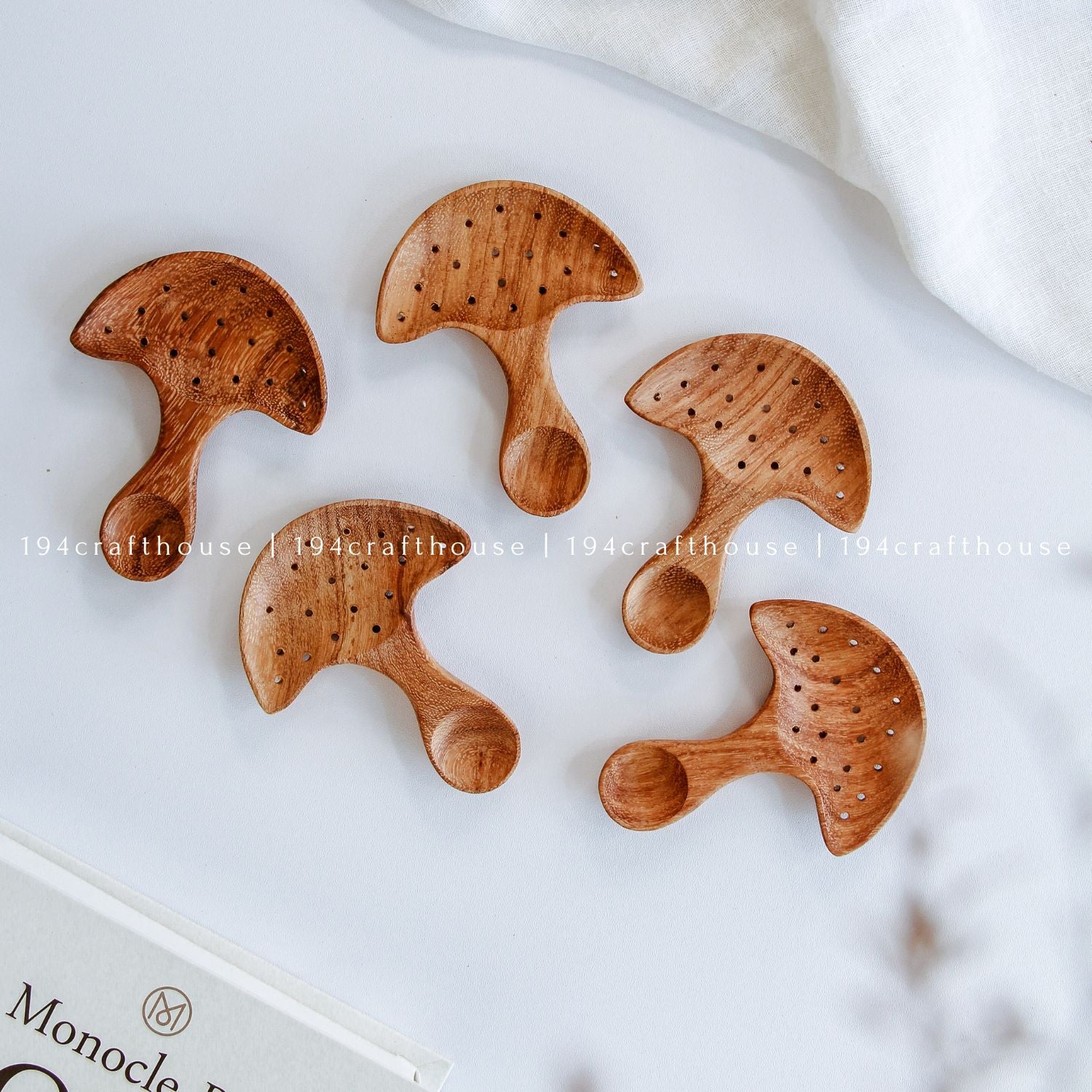Top-down view of a five of hand-carved Doussie wood mushroom spoon centered on a smooth white surface, handmade by 194 Craft House