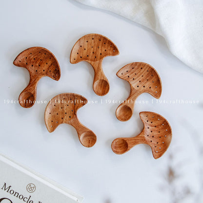 Top-down view of a five of hand-carved Doussie wood mushroom spoon centered on a smooth white surface, handmade by 194 Craft House
