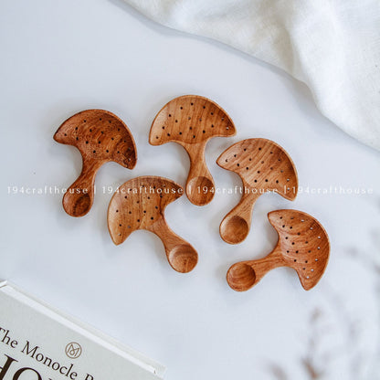 Top-down view of a five of hand-carved Doussie wood mushroom spoon centered on a smooth white surface, handmade by 194 Craft House
