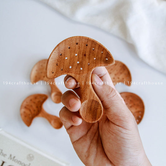Hand-carved Doussie wood mushroom spoons with organic cap handles lined up on a solid white background.