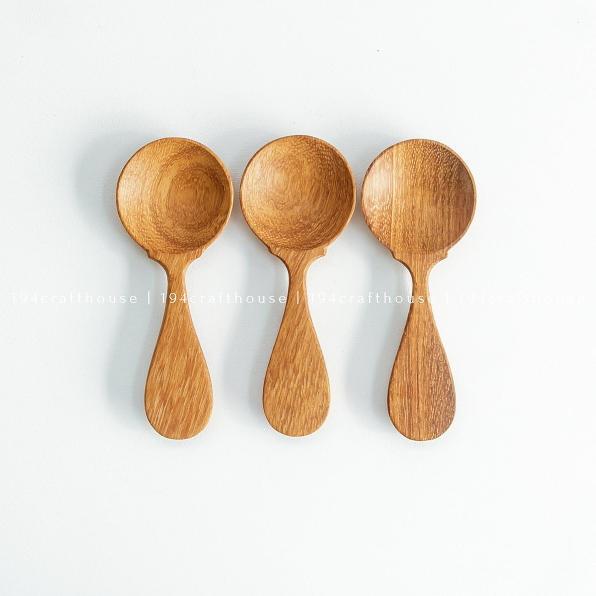 Three wooden spice measuring spoons arranged in a row on white