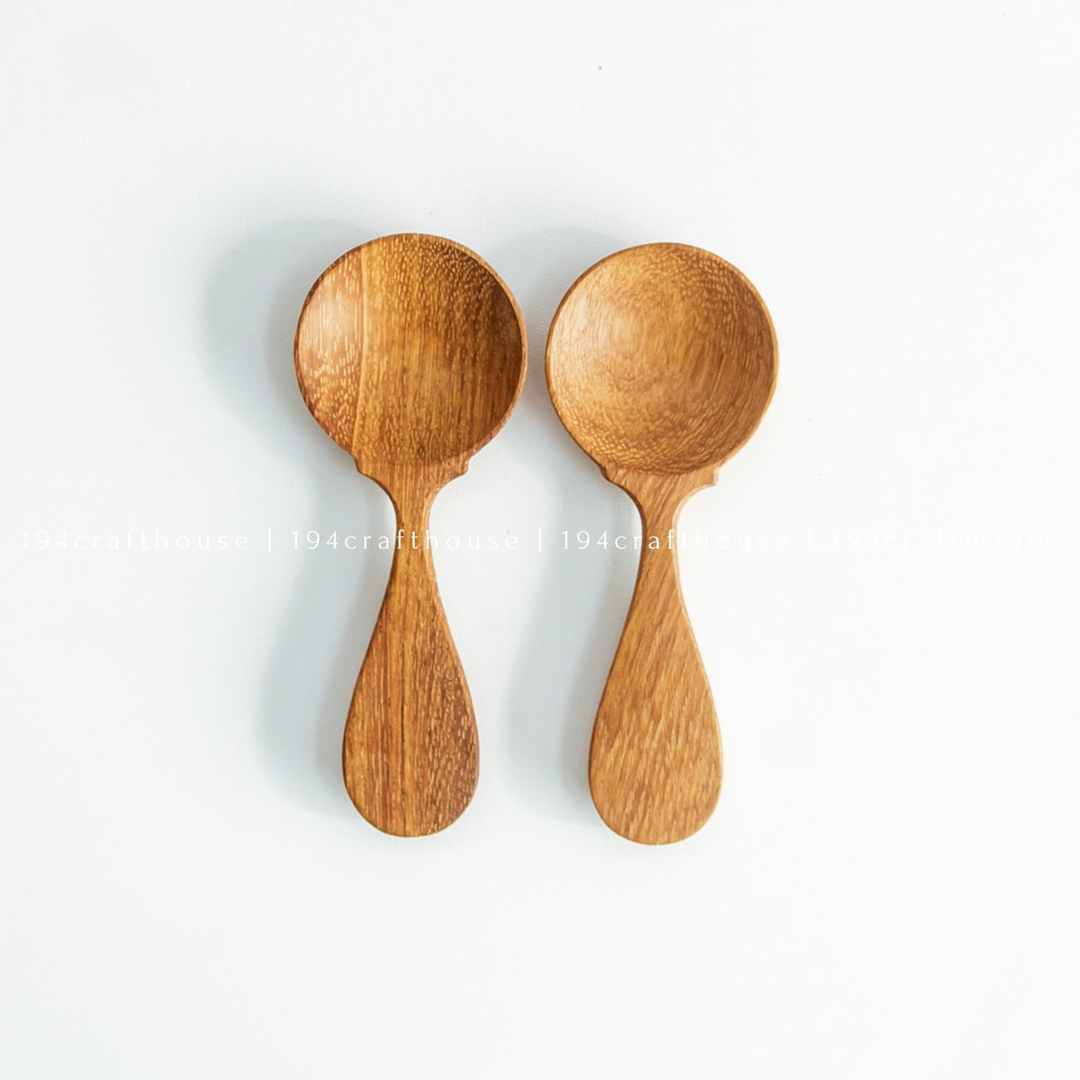 Two wooden spice measuring spoons arranged side by side on white