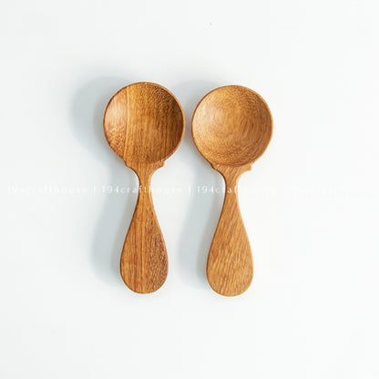 Two wooden spice measuring spoons arranged side by side on white