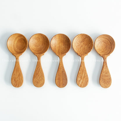 Five wooden spice measuring spoons arranged in a row on white