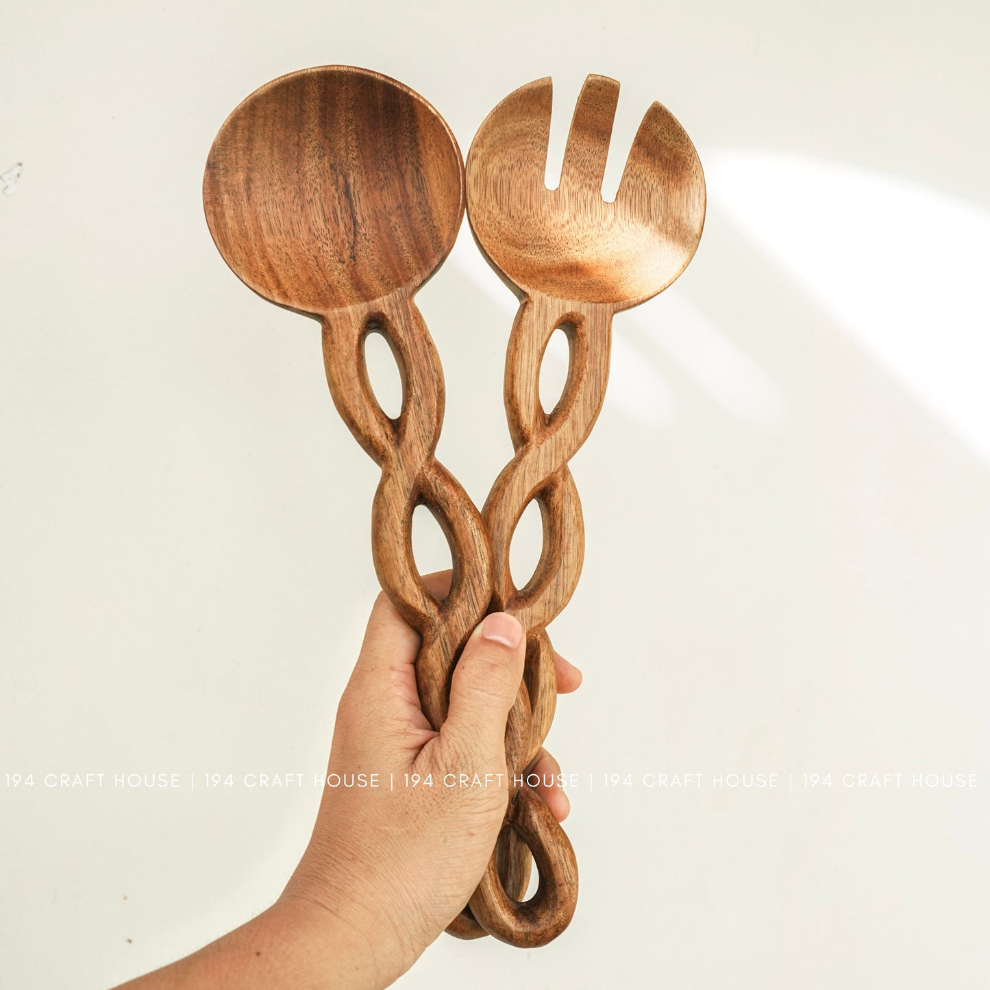Handcrafted chain-handle wooden salad servers held in hand to show their size and artisan details