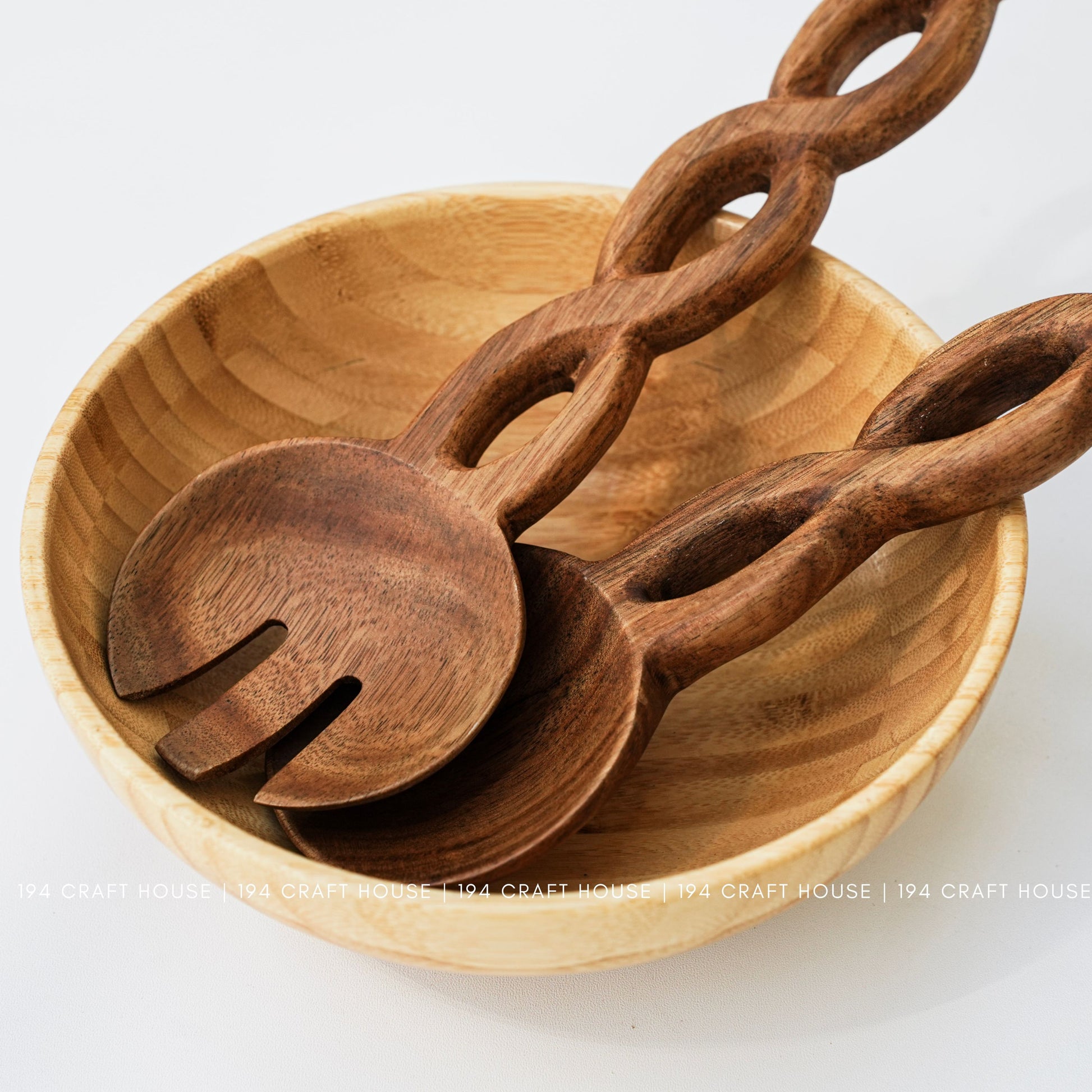 Handcrafted chain-handle wooden salad servers displayed in a wooden serving bowl