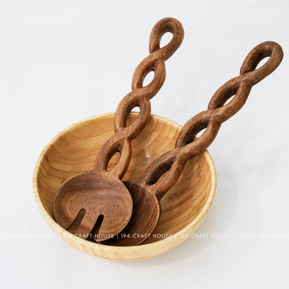 Twisted-handle serving utensils are shown resting in a light-colored bowl.