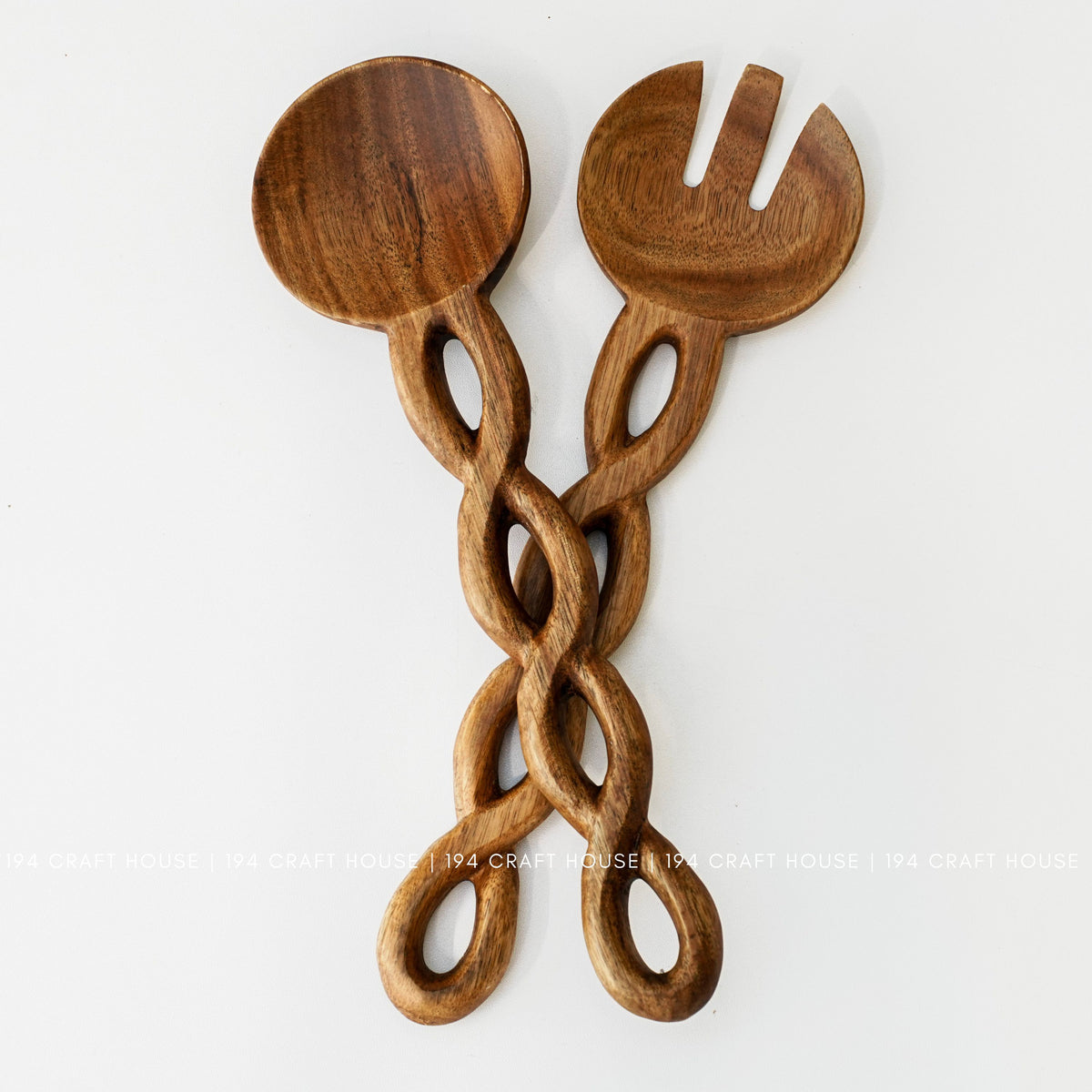 Warm brown serving spoon and fork-shaped utensil with twisted open-loop handles shown together.