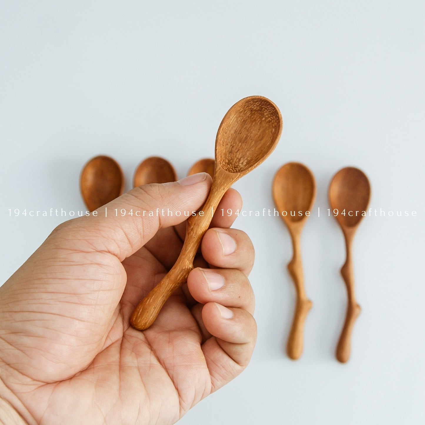 Hand holding a handcrafted twig handle wooden spice spoon with a mini scoop bowl