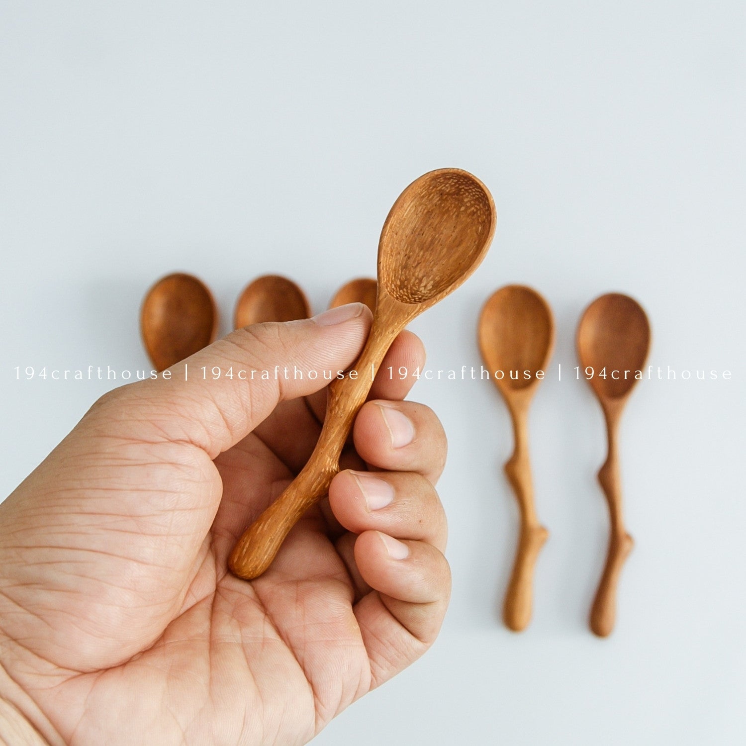 Hand holding a handcrafted twig handle wooden spice spoon with a mini scoop bowl
