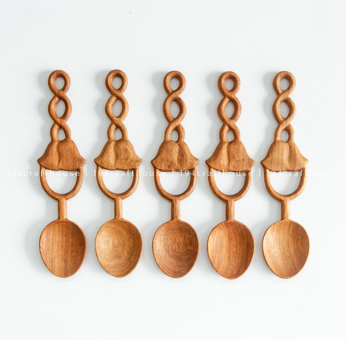 Five Doussie wood spoons arranged side by side, showing their carved bell-shaped loop handles.