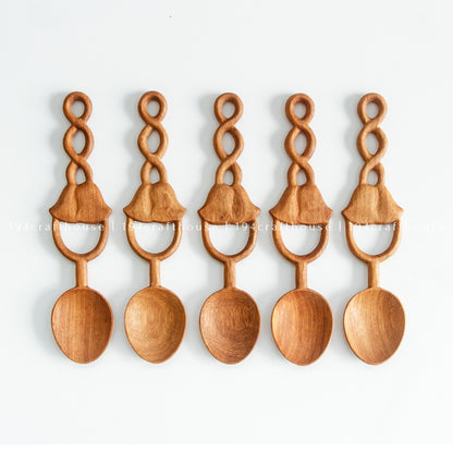 Five Doussie wood spoons arranged side by side, showing their carved bell-shaped loop handles.