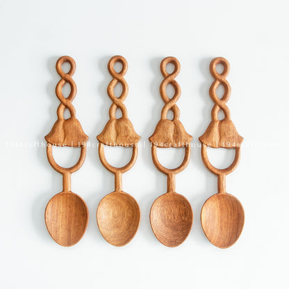 Four Doussie wood spoons aligned on a pale background to show variations in grain and carving.