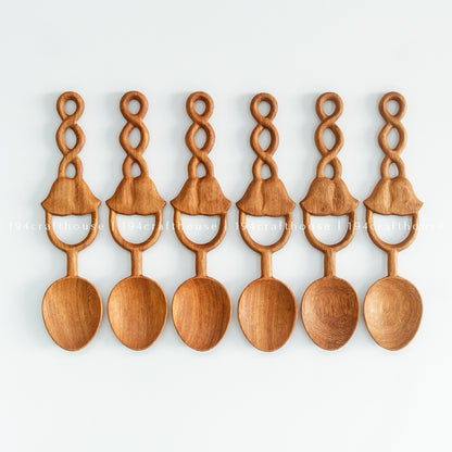 Six Doussie wood spoons in a row on a pale background, showing natural wood color and grain variation.
