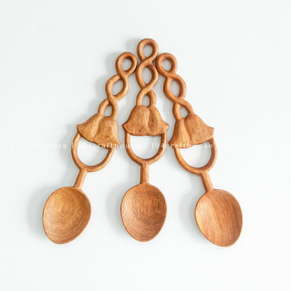 Three Doussie wood spoons arranged in a fan, showing rounded bowls and decorative carved loop handles.