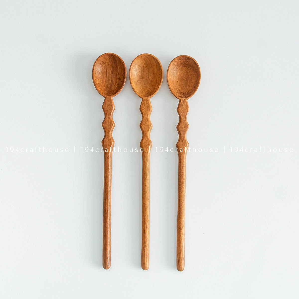Three long wooden measuring spoons aligned vertically showing bowls and handles