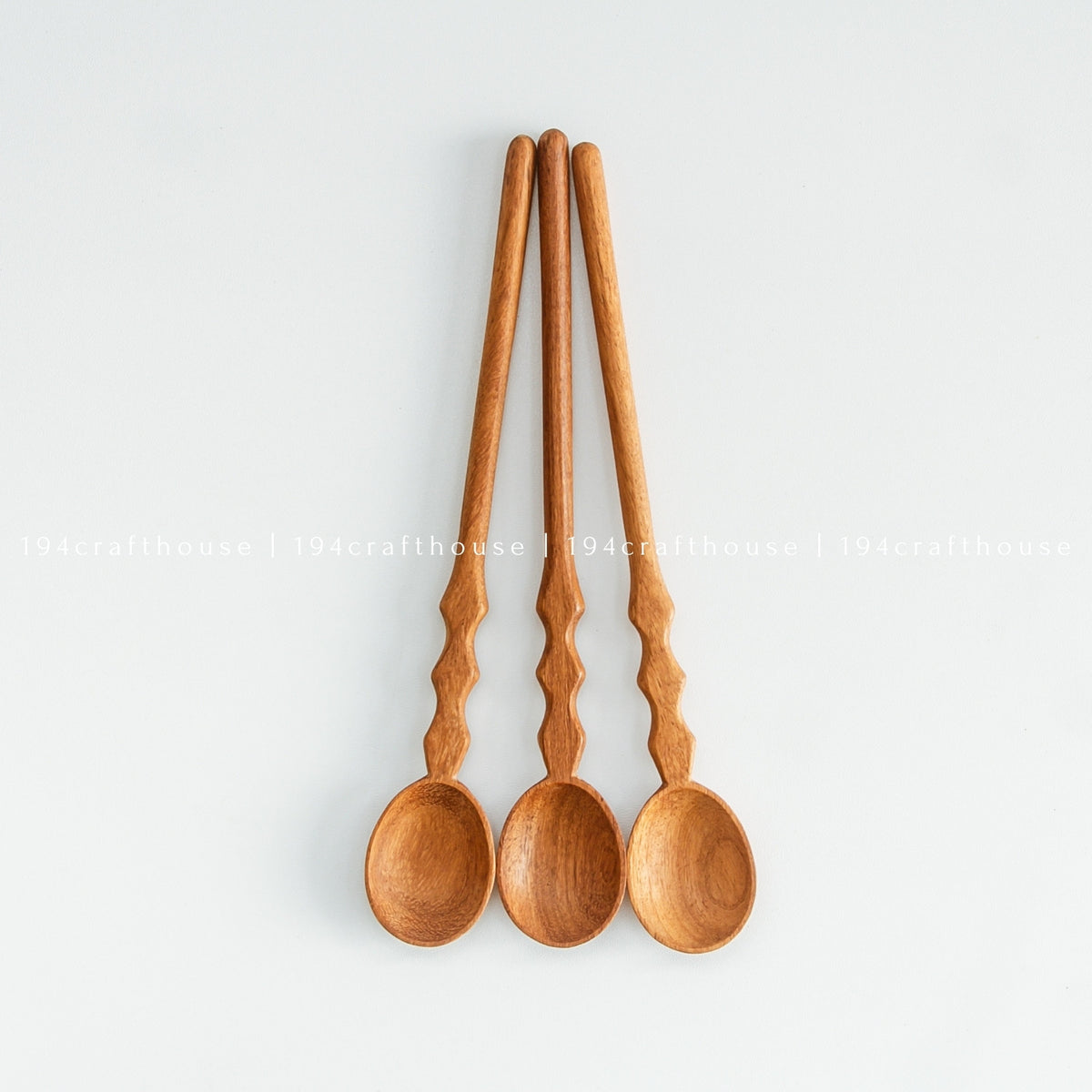 Close-up top view of three wooden spoon handles with bowls visible at bottom