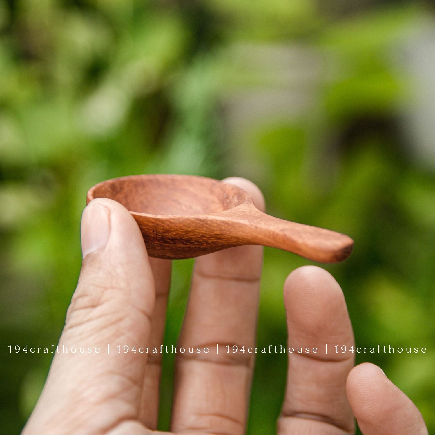 Hand holding a mini wooden spoon for spices, salt, sugar, tea, and other small dry ingredients