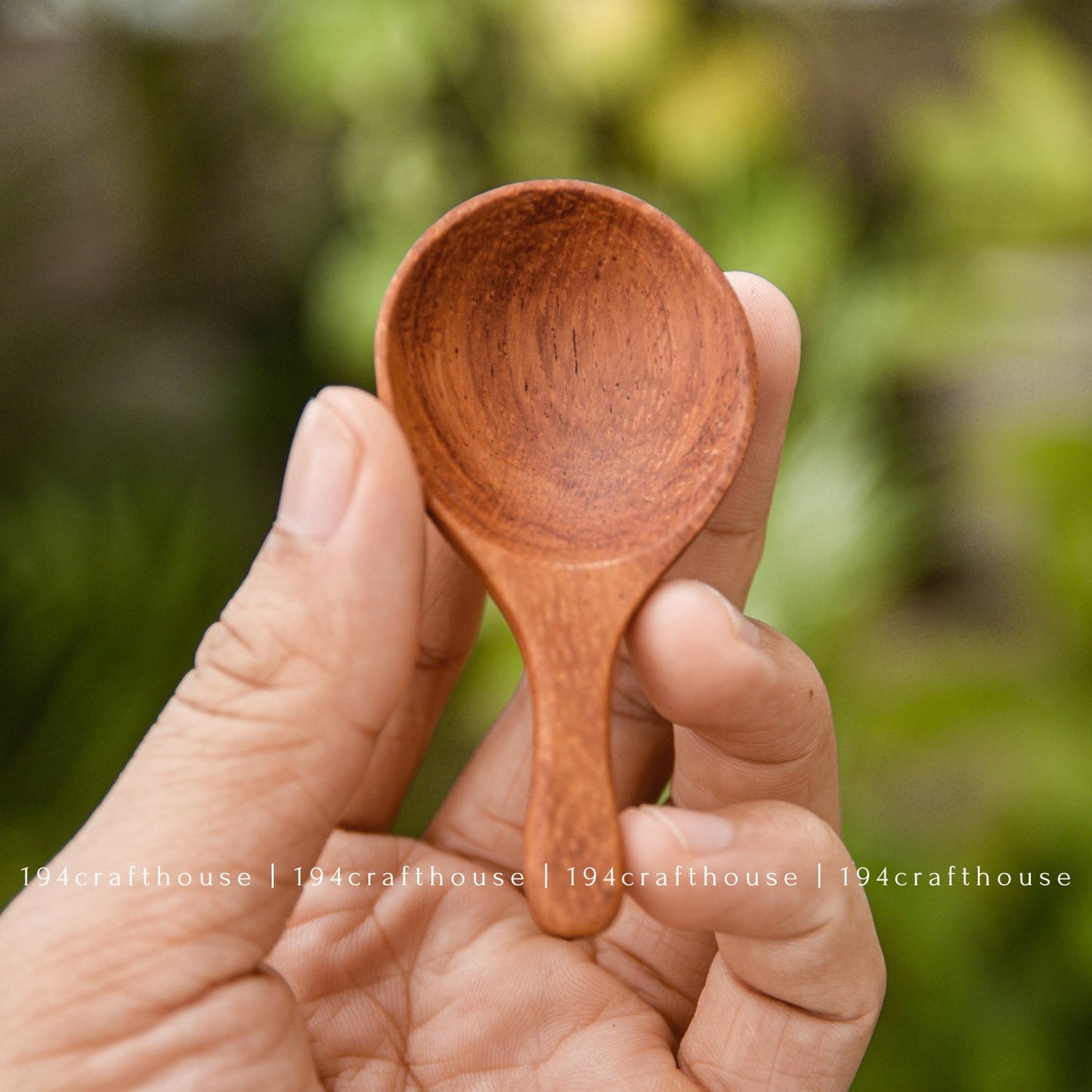 Hand holding a small wooden spoon for scooping spices, sugar, salt, tea, and coffee