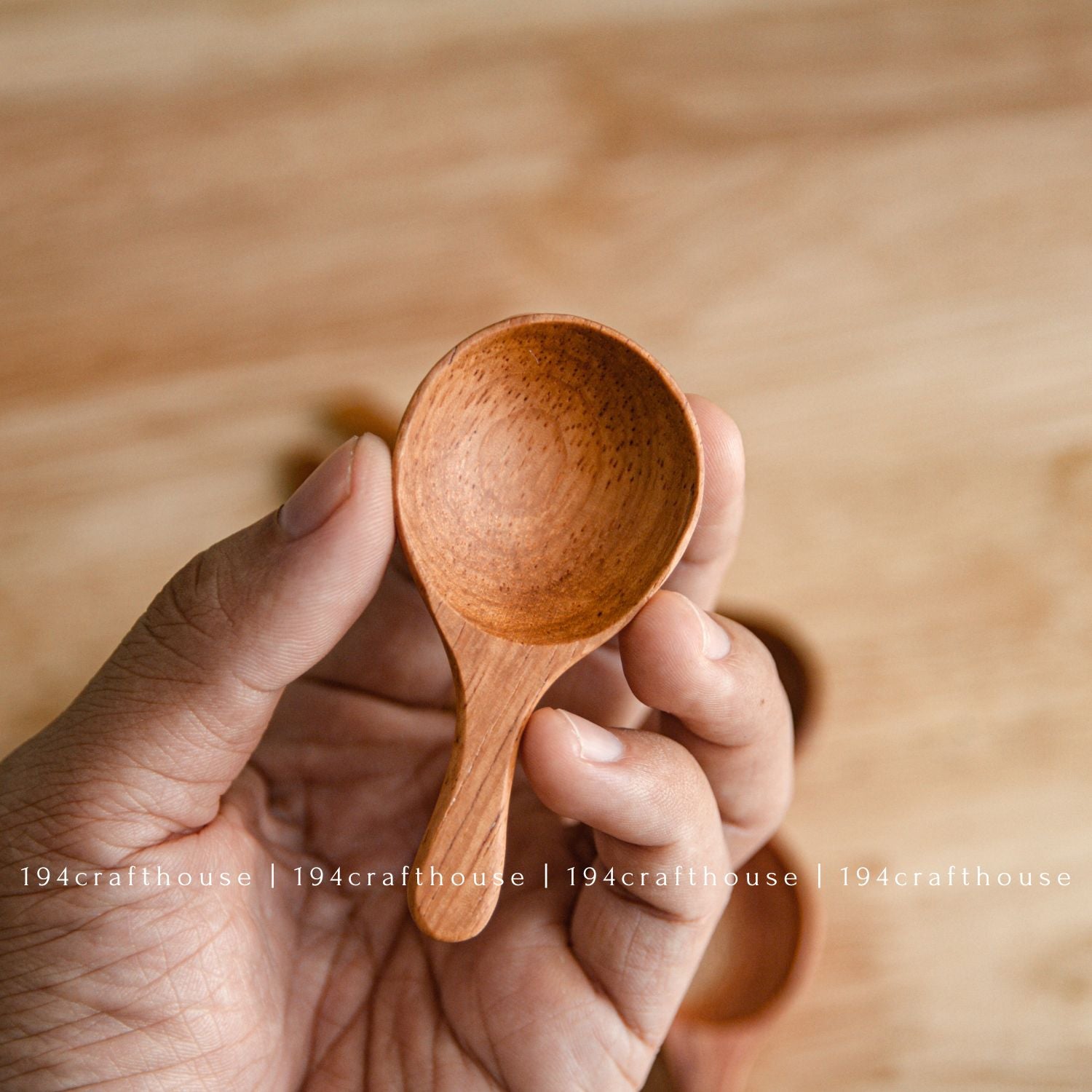 Hand holding a wooden spice spoon to show its size and shaped