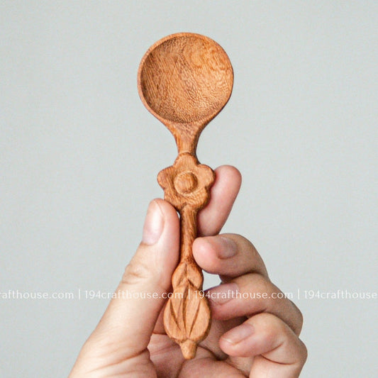 Handcrafted flower-handle wooden spice spoon held in hand to show its size, carved details, and natural wood grain