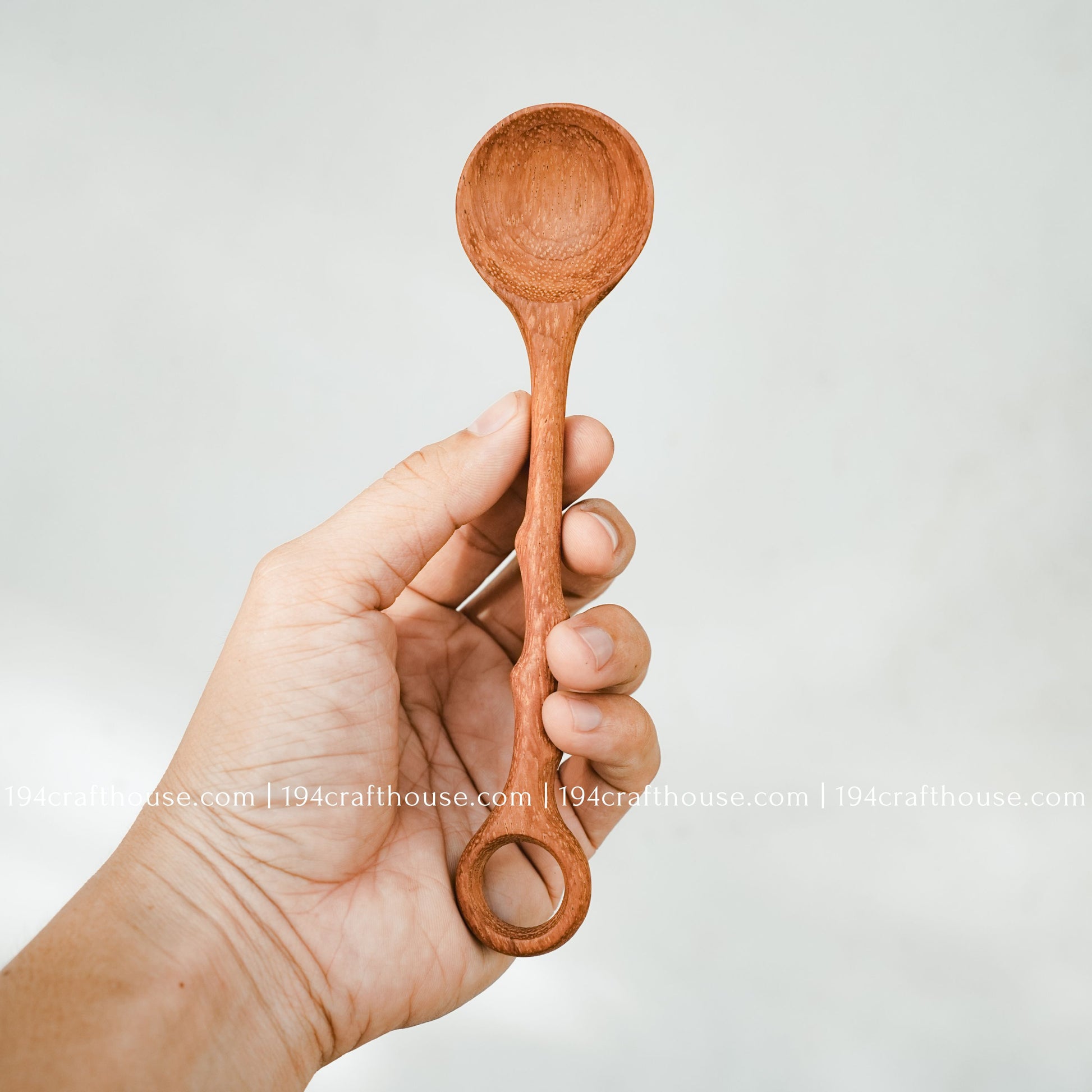 Branch-tree wooden stirring spoon held in hand to show its size, carved handle, and handcrafted finish