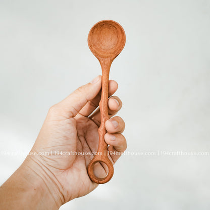 Branch-tree wooden stirring spoon held in hand to show its size, carved handle, and handcrafted finish