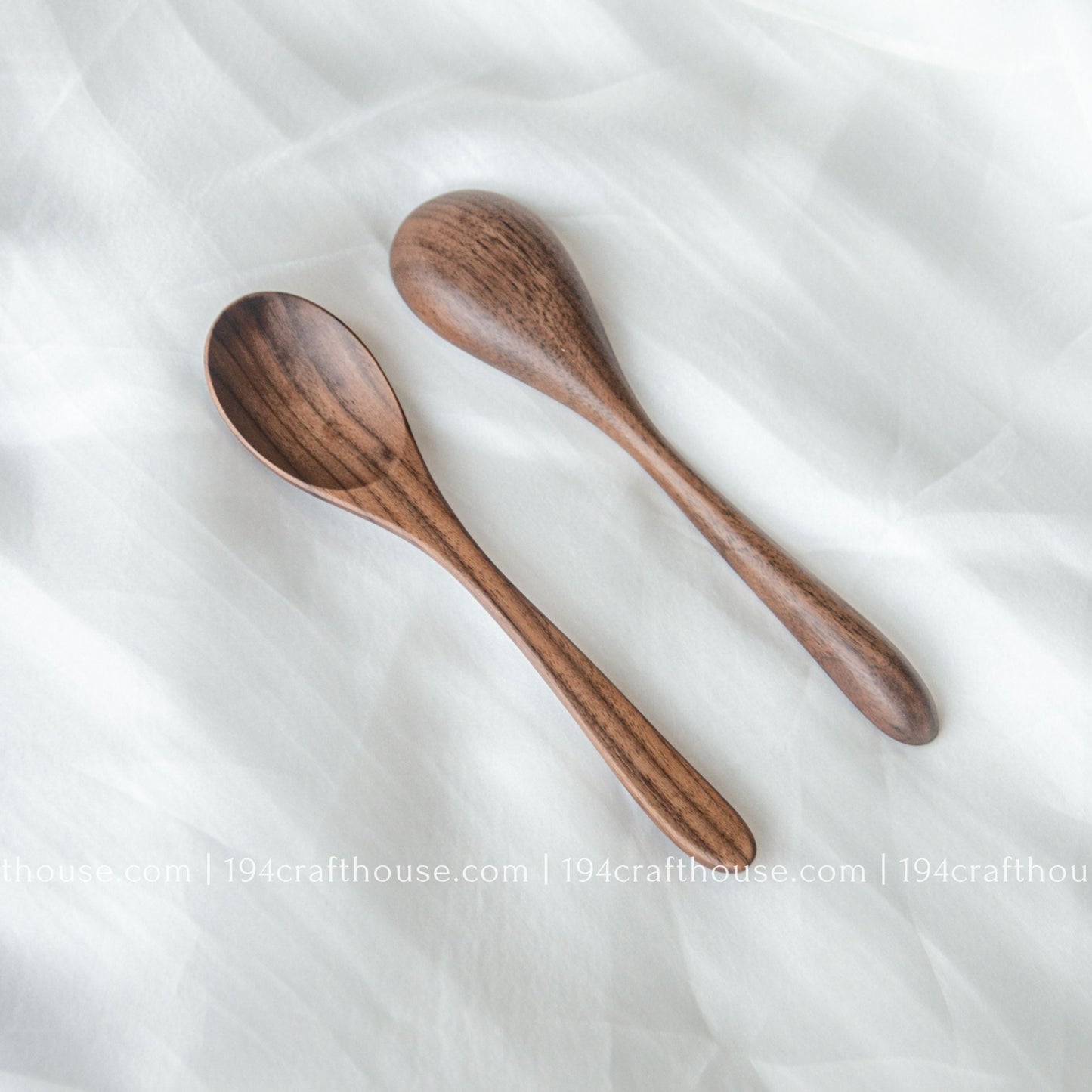 Two handcrafted walnut wooden spoons showcasing smooth finishes and unique natural wood grain variations