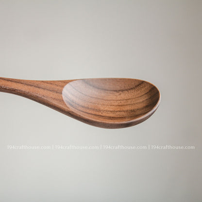 Close-up side view of a handcrafted walnut wooden spoon with a smooth finish and natural wood grain