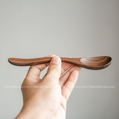 7-inch walnut wooden spoon balanced in hand to demonstrate its length, thickness, and lightweight design