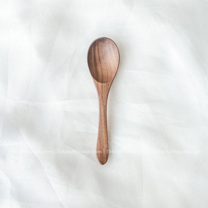 Handcrafted 6-inch walnut wooden spoon displayed on a soft fabric background highlighting its smooth finish and natural walnut wood grain