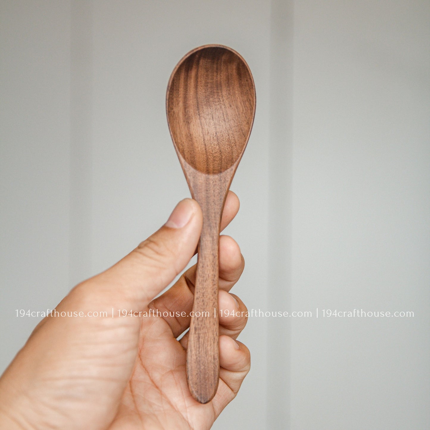 6-inch walnut wooden spoon held in hand to show its size, rounded bowl, and natural walnut wood grain