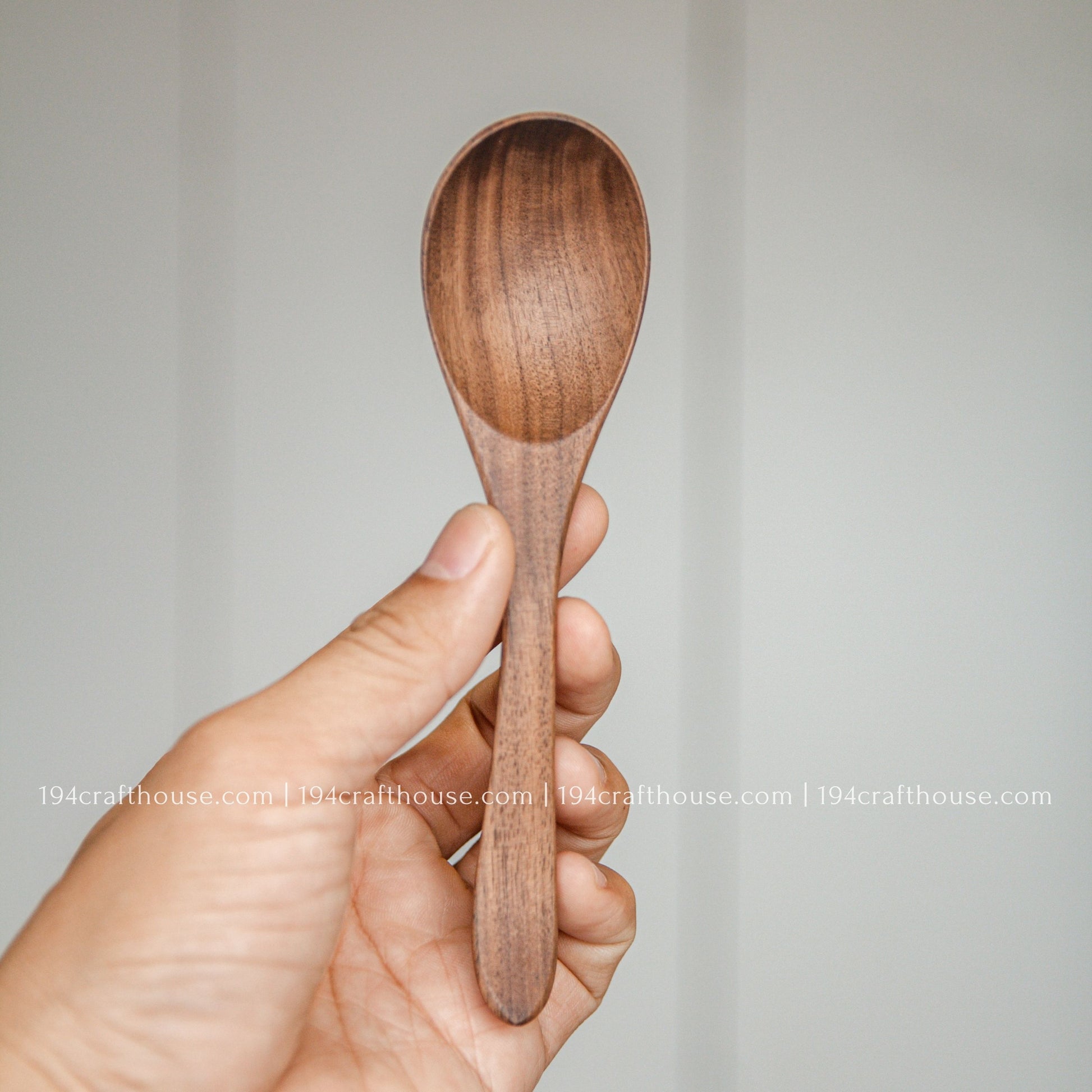 6-inch walnut wooden spoon held in hand to show its size, rounded bowl, and natural walnut wood grain