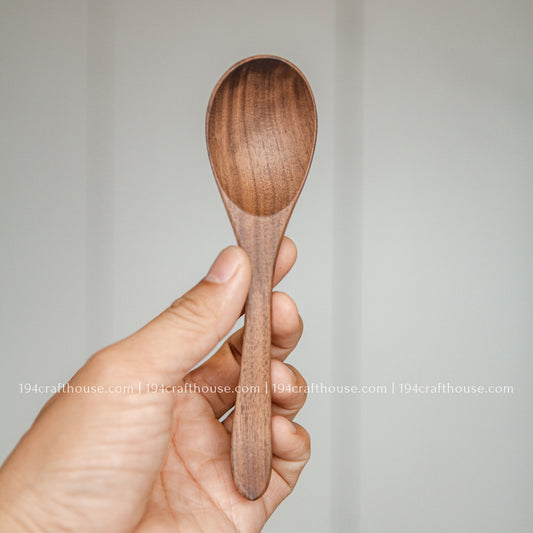 6-inch walnut wooden spoon held in hand to show its size, rounded bowl, and natural walnut wood grain