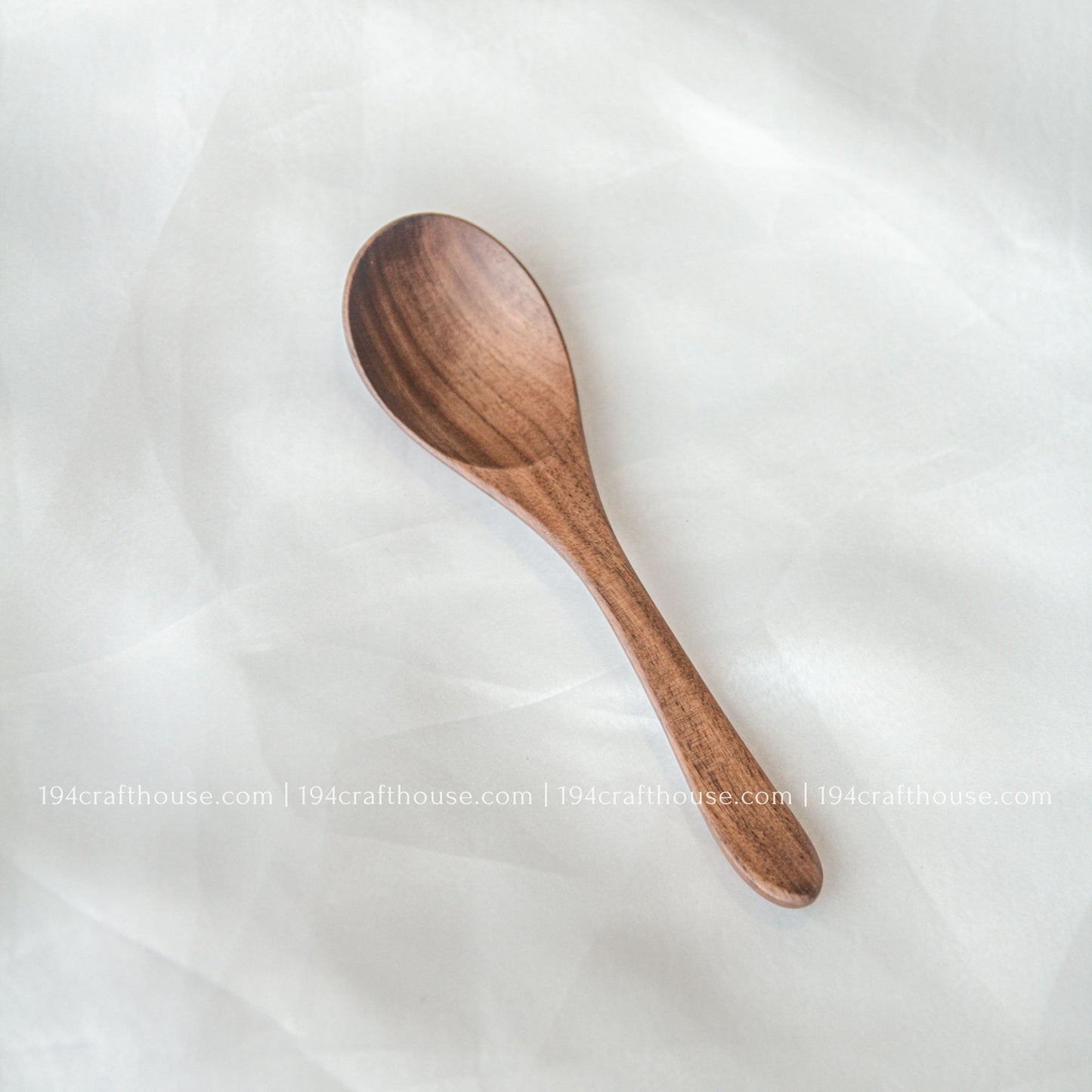 Handcrafted 6-inch walnut wooden spoon displayed on a soft fabric background with natural walnut wood grain