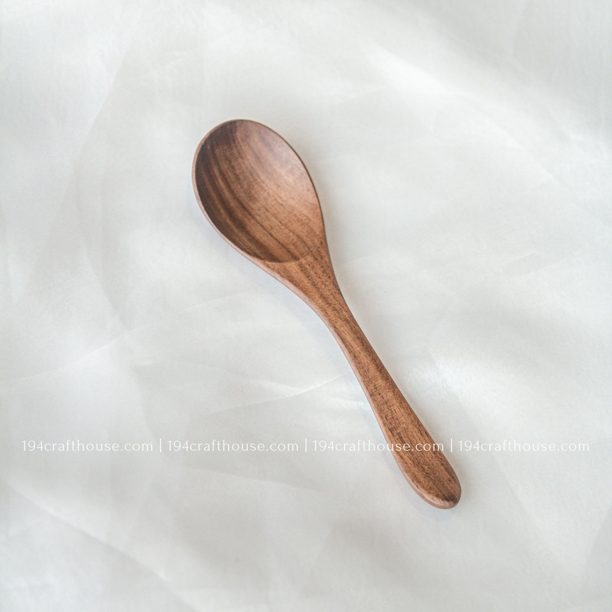 Handcrafted 6-inch walnut wooden spoon displayed on a soft fabric background with natural walnut wood grain