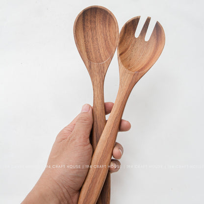 Hand holding acacia wood salad spoon and fork to show handle size and grip