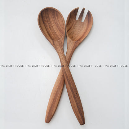 Acacia wood salad spoon and fork crossed on a white background, warm brown grain