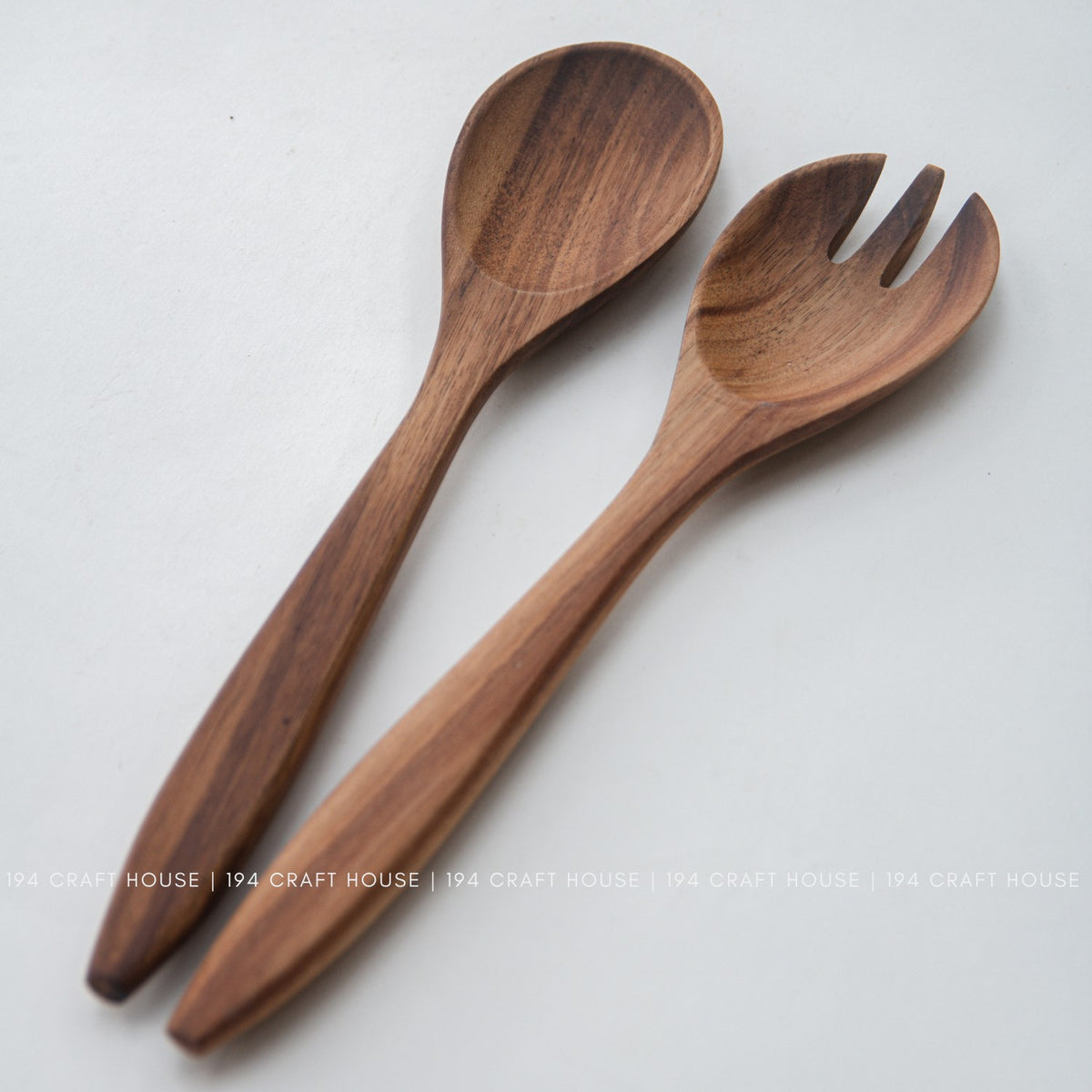 Acacia wood salad spoon and fork side by side showing tapered handles and dark grain streaks