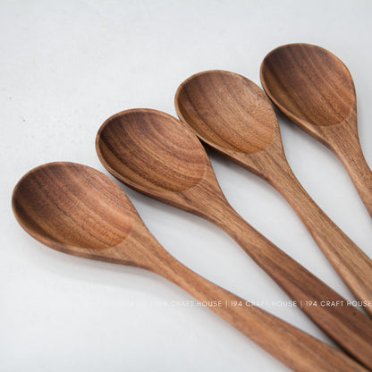 Angled close-up of four acacia wood salad spoons with smooth rounded bowls
