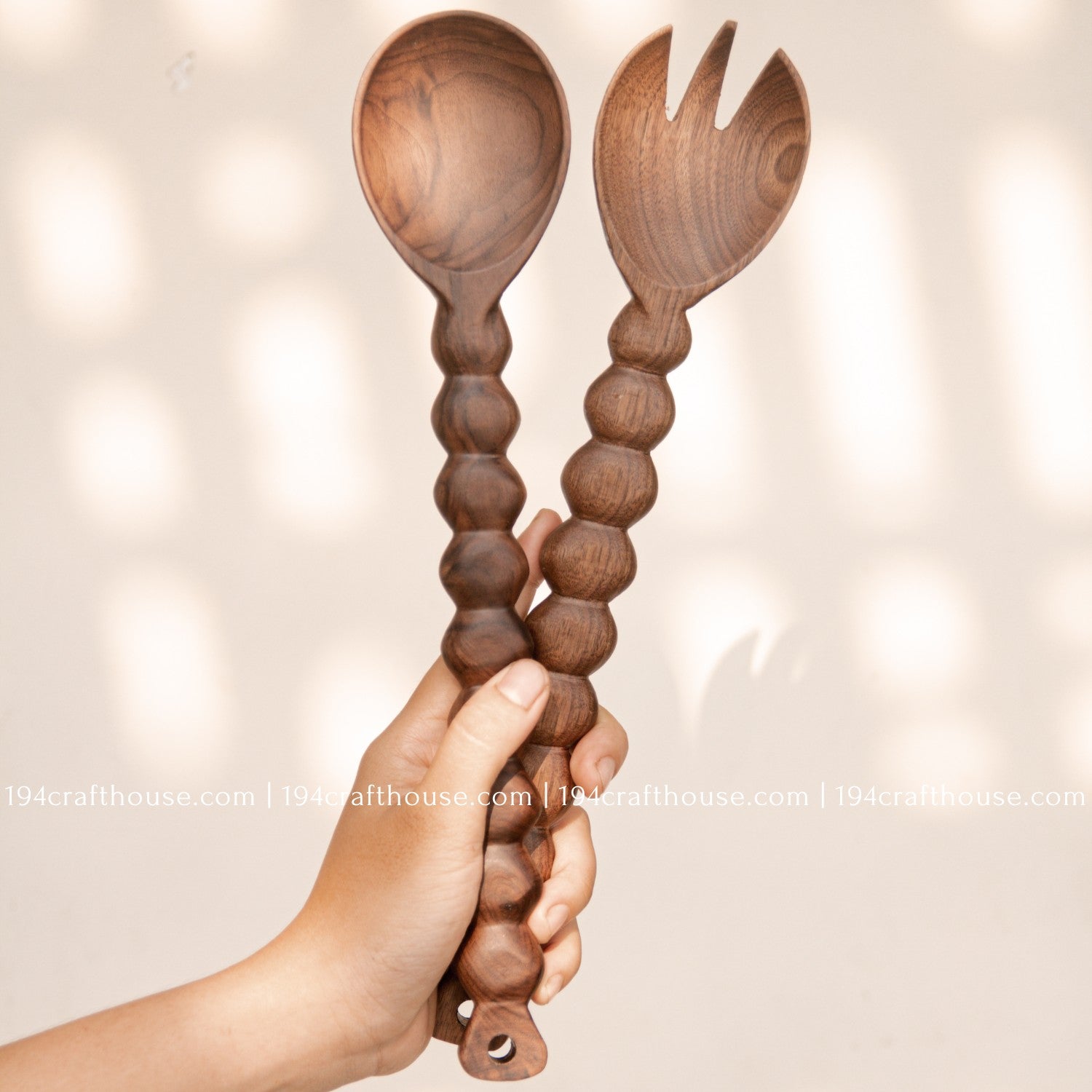 Large walnut wood salad serving spoon with decorative carved handle held in hand