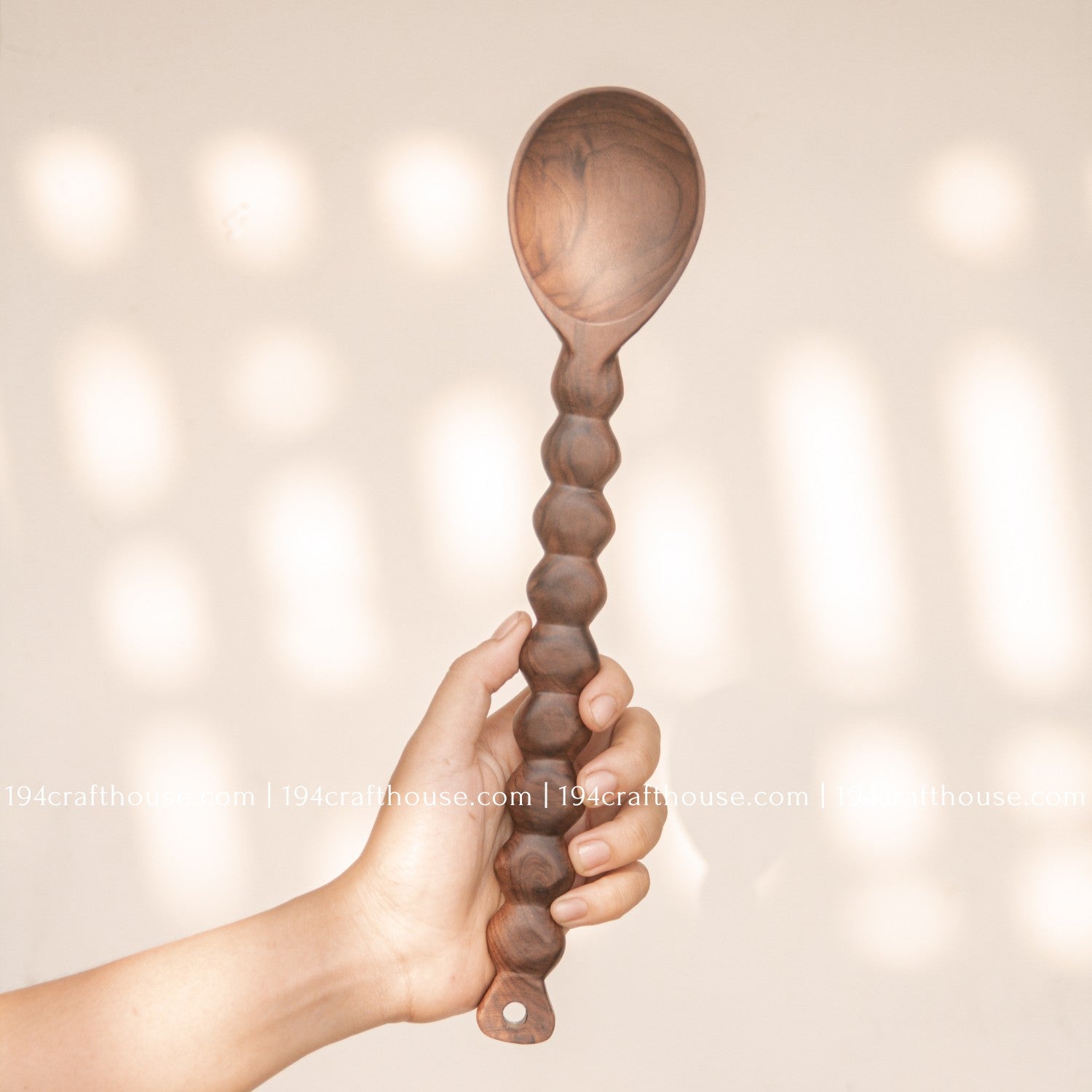 Handcrafted walnut wood salad servers with beaded handles, featuring a serving spoon and fork set hold by hand by 194 Craft House.