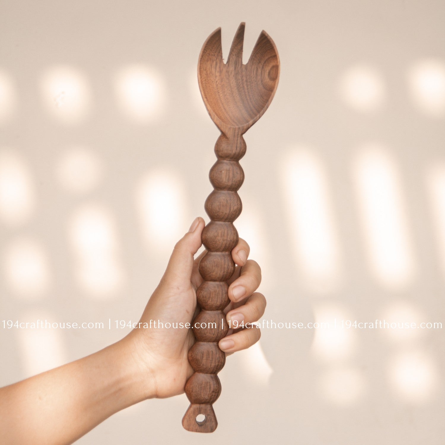 Handcrafted walnut wood salad spoon with beaded handles, featuring a serving spoon and fork set hold by hand by 194 Craft House.